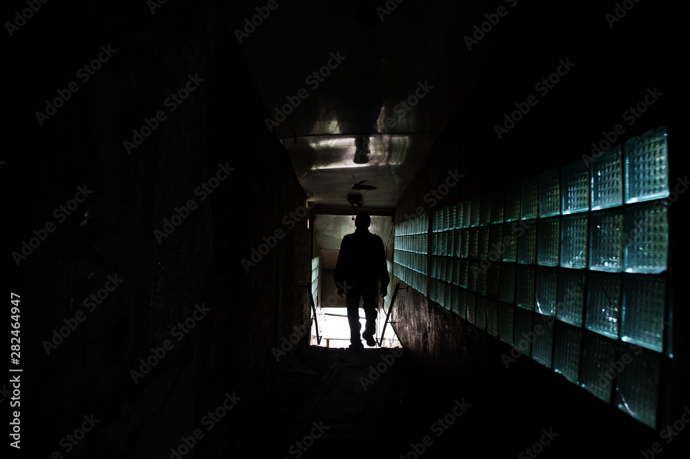 Industrial interior of an old abandoned factory. Man in shadow tonnel. Scary concept.