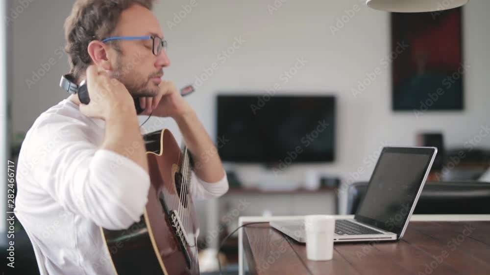 Man playing acoustic guitar in the living room. Man playing acoustic guitar in the living room.