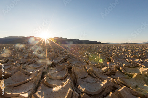 Cracked playa mud texture from the desert to the mountains at sunset photo