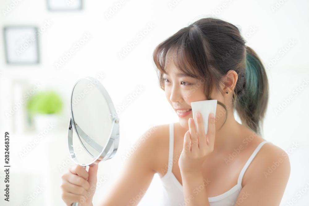 Beautiful young asian woman smile and joy with skin care use oil blotting paper on face looking mirror in the room, beauty asia girl happy and cheer makeup and cosmetic, health care on facial concept. Beautiful young asian woman smile and joy with skin care use oil blotting paper on face looking mirror in the room, beauty asia girl happy and cheer makeup and cosmetic, health care on facial concept.