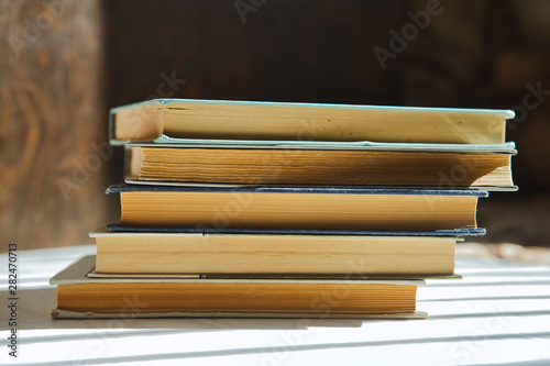 Stack of books on wooden background with beautiful shadows