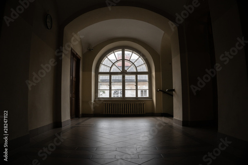Half-round vintage window in a dark corridor of an 18th century building. © Dmytro