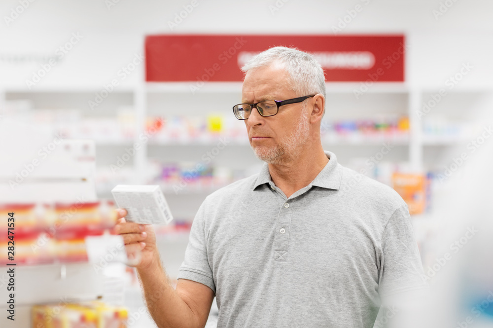 medicine, pharmaceutics, healthcare and people concept - senior male customer with drug at pharmacy medicine, pharmaceutics, healthcare and people concept - senior male customer with drug at pharmacy