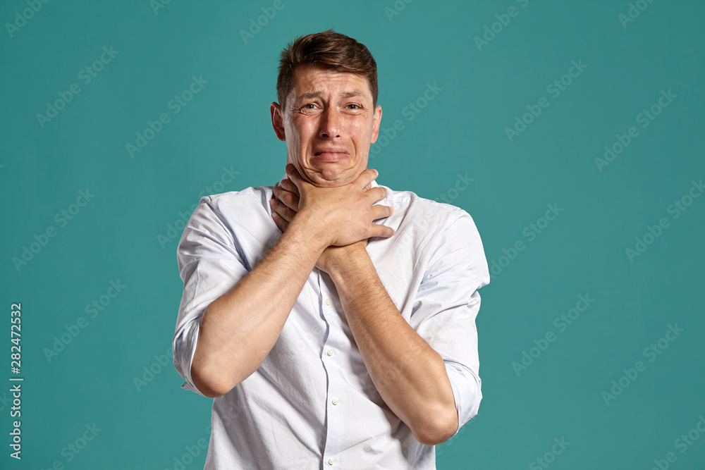 Young man in a classic white shirt is posing over a blue background. Young man in a classic white shirt is posing over a blue background.