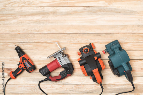 Set of hand carpentry power tools for woodworking lies on a light wooden background. Directly above