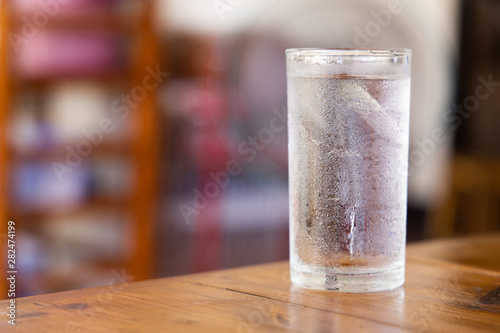 A glass of cold water on a wooden table.