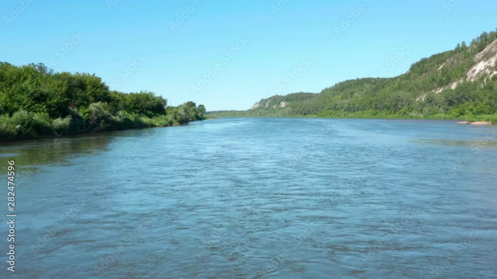 The copter flies in the middle of the river. The camera follows the river close to the water.River between the rocky mountains and forest. The copter flies in the middle of the river. The camera follows the river close to the water.River between the rocky mountains and forest.
