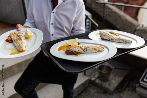 waiter serves dishes with fish