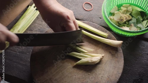 Old lady use knife for slicing lemon grass. Preparing for cooking.