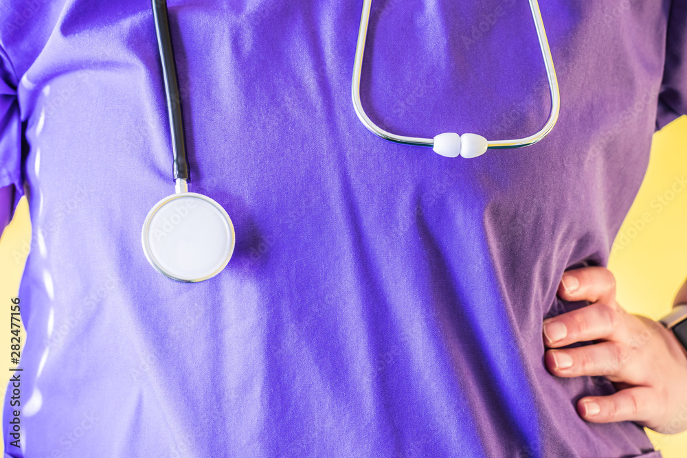 Front View of a woman doctor in purple scrubs with stethoscope Front View of a woman doctor in purple scrubs with stethoscope