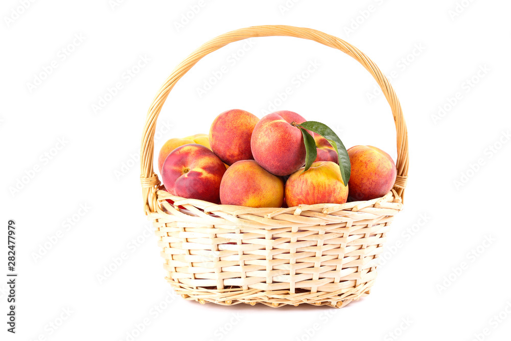 Fresh peaches with green leafs in basket isolated on white background