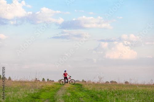 Girl on a bicycle on a background of blue sky and green grass