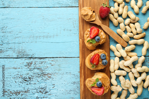 Bread with peanut butter, fruits and nuts on wooden table