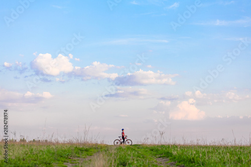 Girl on a bicycle on a background of blue sky and green grass