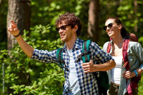 travel, tourism, hike and people concept - mixed race couple with backpacks in forest