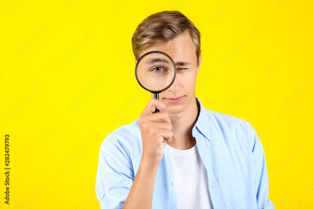 Young man with magnifying glass on yellow background Young man with magnifying glass on yellow background