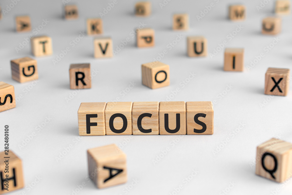 Focus - word from wooden blocks with letters, main object or interest most important thing concept, random letters around, white background Focus - word from wooden blocks with letters, main object or interest most important thing concept, random letters around, white background