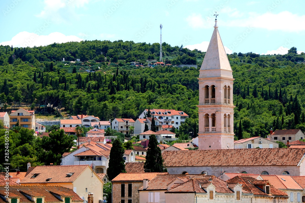 Traditional stone architecture and landmark Church of Mary's Annunciation bell tower in small town Supetar, on island Brac, Croatia.