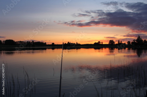 Fishing on the lake on a warm evening, in the middle of summer. A unique image of the surrounding nature. © jakov