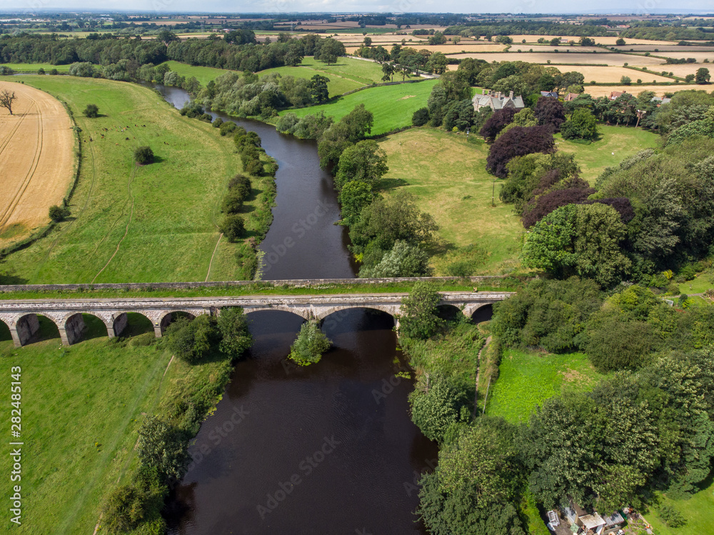 Obraz premium Aerial photo of the the historic Tadcaster Viaduct and River Wharfe located in the West Yorkshire British town of Tadcaster, taken on a bright sunny day
