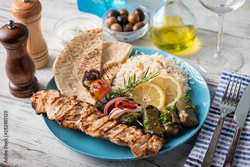 assorted greek food platter with souvlaki, rice, pita and dolmades
