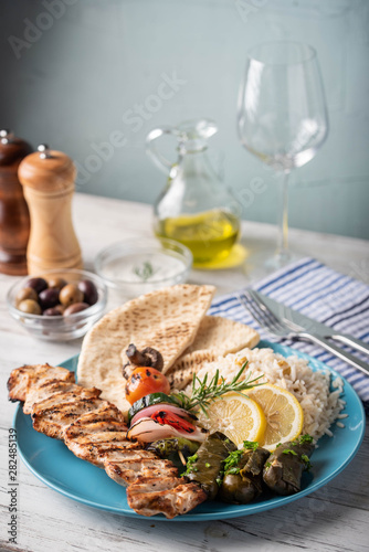 assorted greek food platter with souvlaki, rice, pita and dolmades