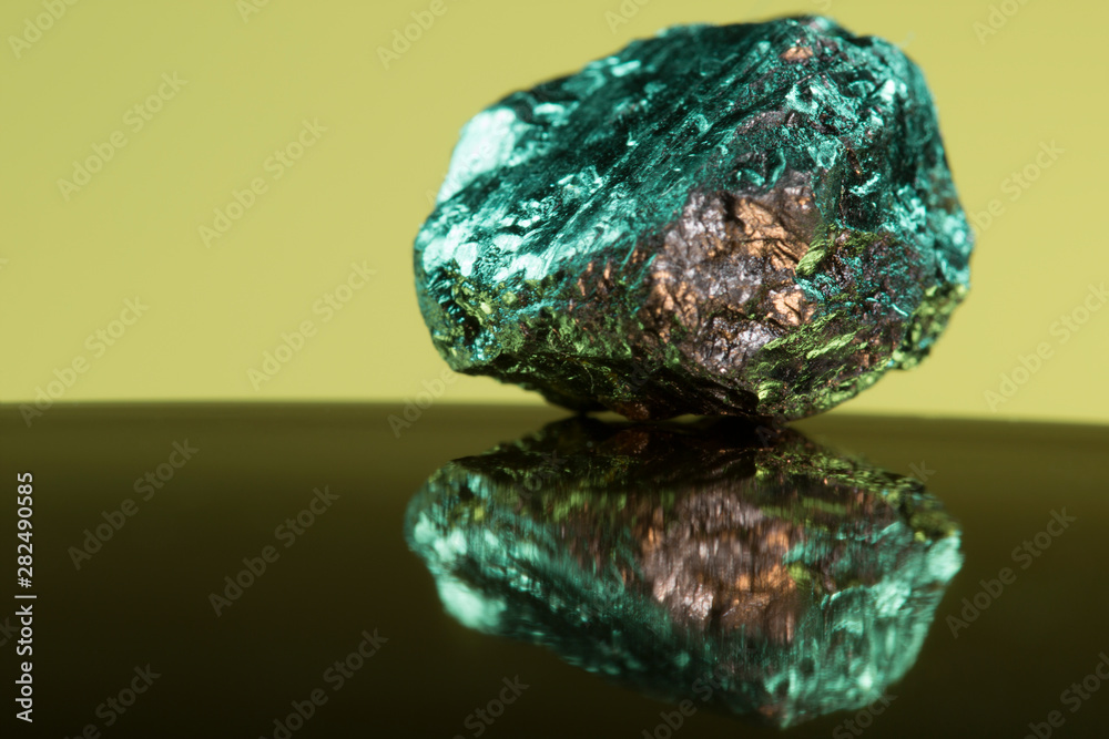Small piece of heavy mineral rock coloured green that has gold features