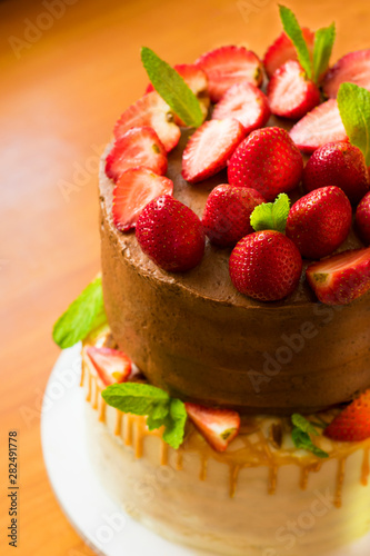 Chocolate cake decorated with fresh strawberries and mint leaves. Cooking Confectionery.