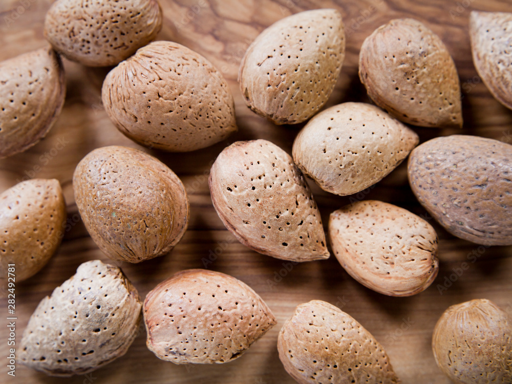 Almond Nuts in shells on the olive wood - wooden board with copy space . Almond Nuts in shells on the olive wood - wooden board with copy space .
