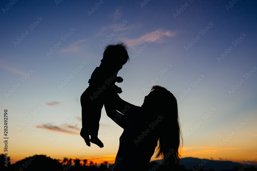 Silhuoete picture with copy space of mother and  her baby in the moment of love and  romantic among the twilight sunset evening time. Concept for love of parents and family.