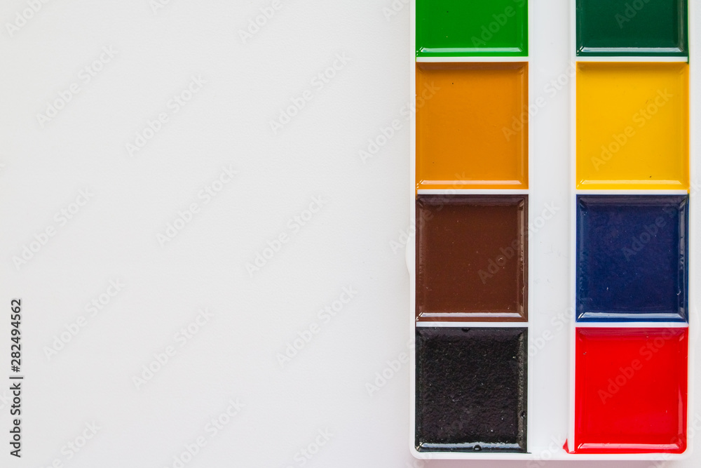 Fototapeta premium The complete set of water colour paints on a white background.Aquarelle colors in a plastic box. Different set of watercolors in palette.Copy space