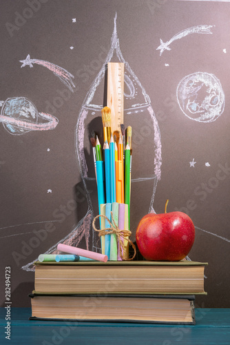 Back to school background. pencils, brushes and rulers, crayons and books lined up in the shape of a rocket. 