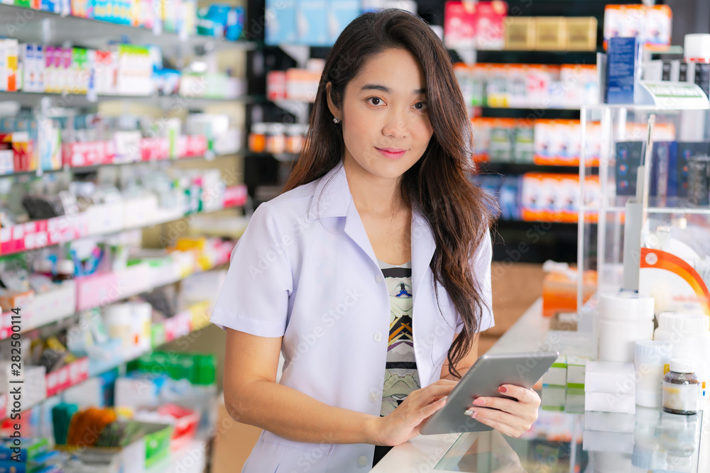 Asian female pharmacist uses digital tablet in the pharmacy