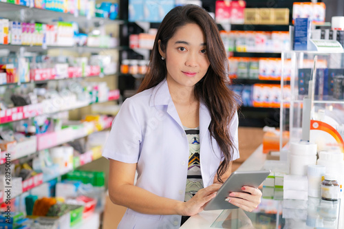 Asian female pharmacist uses digital tablet in the pharmacy