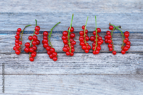 Red currant berries lying in a row on old gray wooden surface, selective focus photo