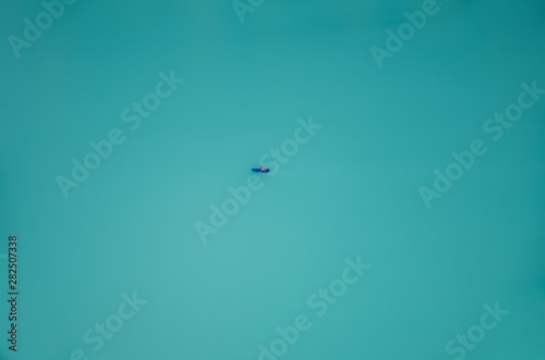 Lone boat sailing at turquoise Oeschinensee in Switzerland. Swiss Oeschinen Lake. Aerial view, blurred boat. Minimalist nature, escape, lost concept. Conceptual, abstract