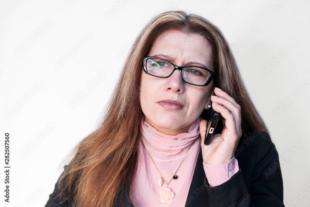 Middle-aged woman in a business suit talking on the phone with a sad face. She cannot agree with customers on discount products Middle-aged woman in a business suit talking on the phone with a sad face. She cannot agree with customers on discount products