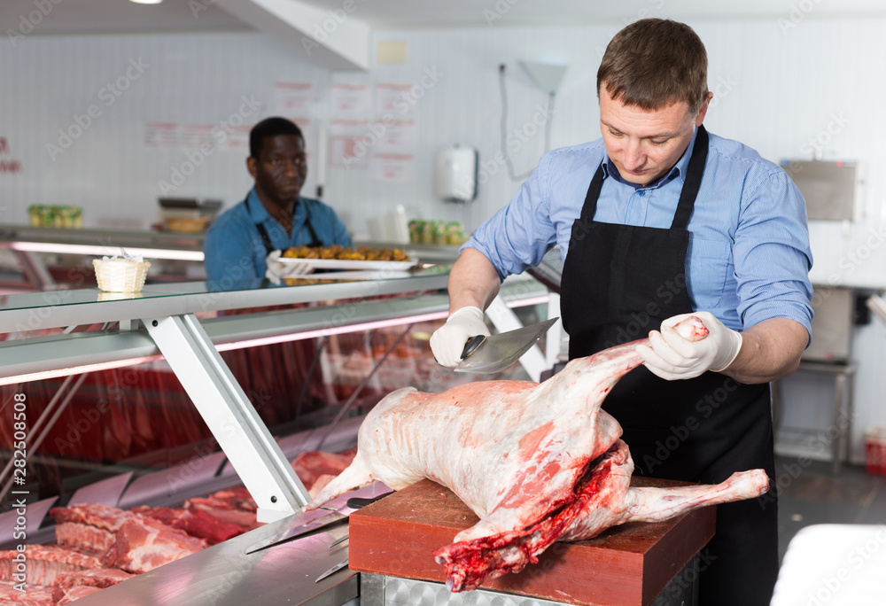 Butcher cutting lamb carcass