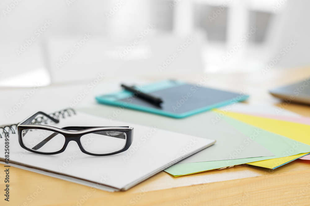 Glasses among the papers. Graphics tablet on the desktop. Free space for text. Office workplace. Glasses among the papers. Graphics tablet on the desktop. Free space for text. Office workplace.