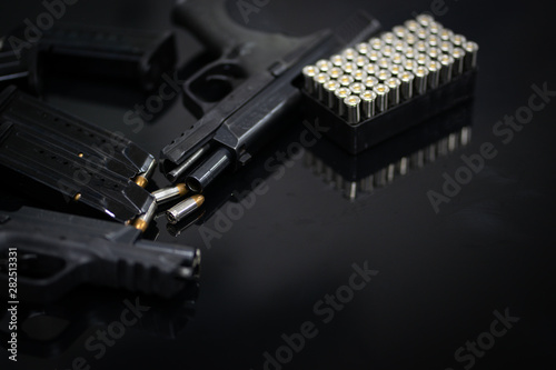 9mm. Black pistol hand gun with bullets and magazine on desk. Selective focus.