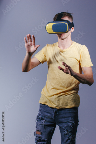 technology, gaming, entertainment and people concept - young man with virtual reality headset or 3d glasses. Studio shot, gray background. © Air_Lady