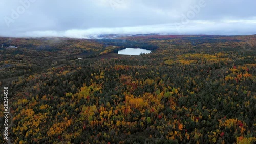 Aerial Forward: Colorful Forest Covered Plain With Lake In Middle And Fog In Distance - Dixville Notch, New Hampshire photo