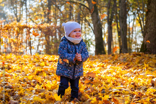 smiling baby girl playing with falling leaves