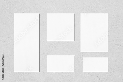 Empty white wedding stationery mockups with soft shadows on neutral light grey concrete wall background. Blank invitation, greeting card, menu, rsvp, table card, thank you card. Flat lay, top view