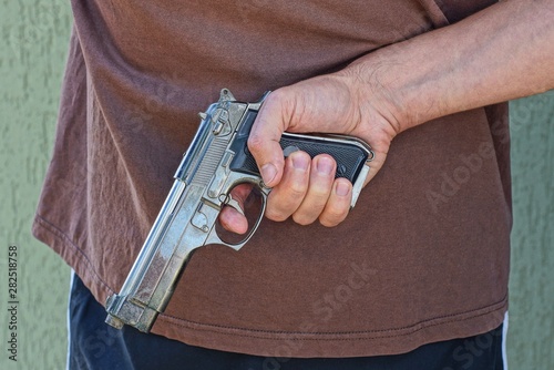 Bilde på lerret hand holds a gun behind a man in brown clothes