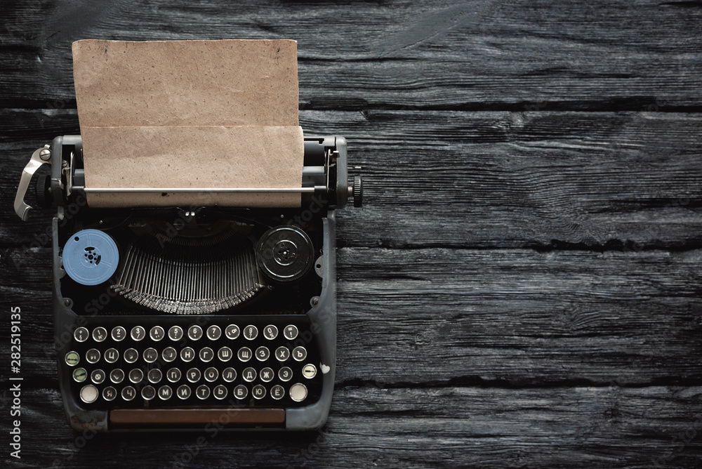 Fototapeta premium Old typewriter on a writer black wooden desk flat lay background with copy space.