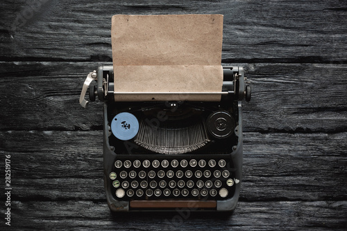 Old typewriter on a writer black wooden desk flat lay background with copy space.