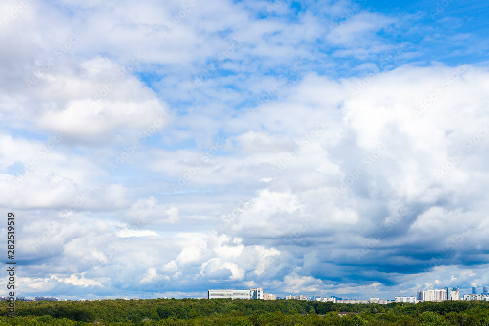 low large white clouds in blue sky over city park low large white clouds in blue sky over city park