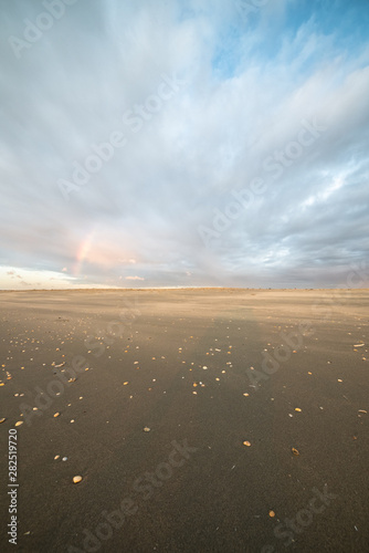 Shower with rainbow on the dutch beach on a windy day