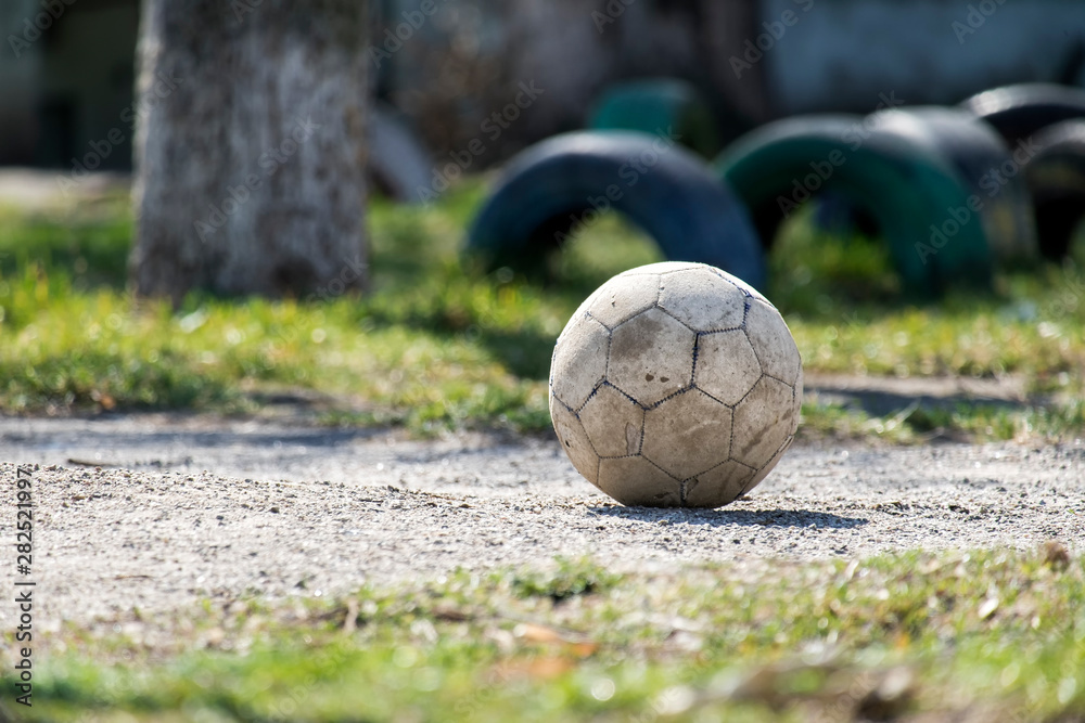 Old shabby leather soccer ball lying on the ground